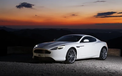 Aston Martin Virage estacionado al atardecer, mostrando su diseño elegante contra un impresionante fondo montañoso.