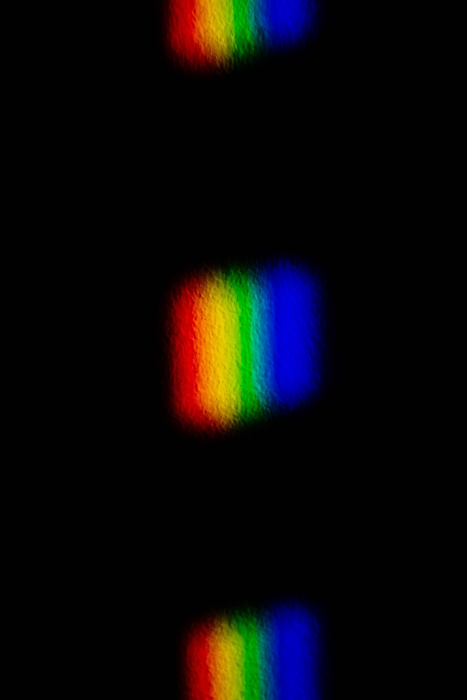 A close up of a rainbow colored light shining on a black background (color, colorfulness, circle, light, darkness)