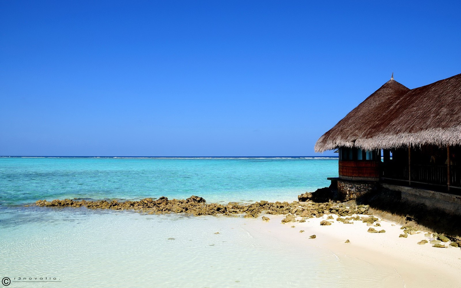 There is a hut on the beach with a thatched roof (beach, sea, ocean, tropics, vacation)