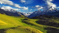 Ein atemberaubender Blick auf das Himalaya-Gebirge, das üppige grüne Täler und zerklüftete Gipfel unter einem lebhaften Himmel zeigt.