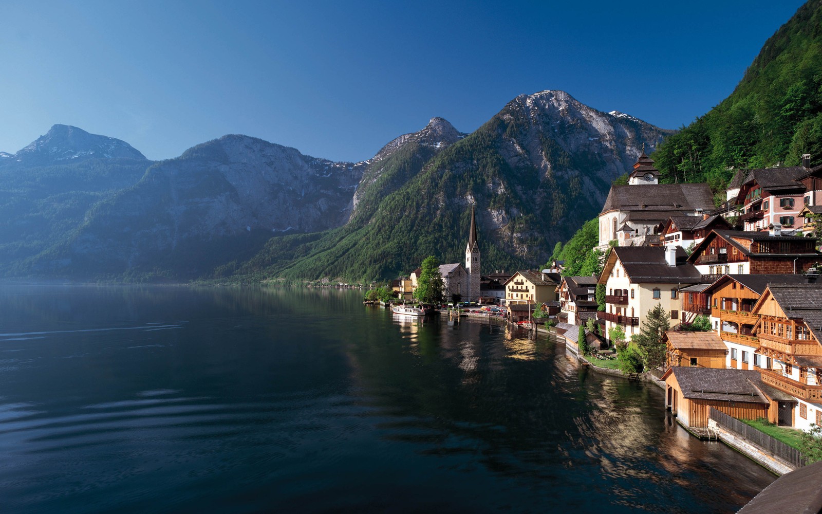 Une vue d'une ville au bord d'un lac avec des montagnes en arrière-plan (hallstatt, lac, montagne, formes montagneuses, village de montagne)