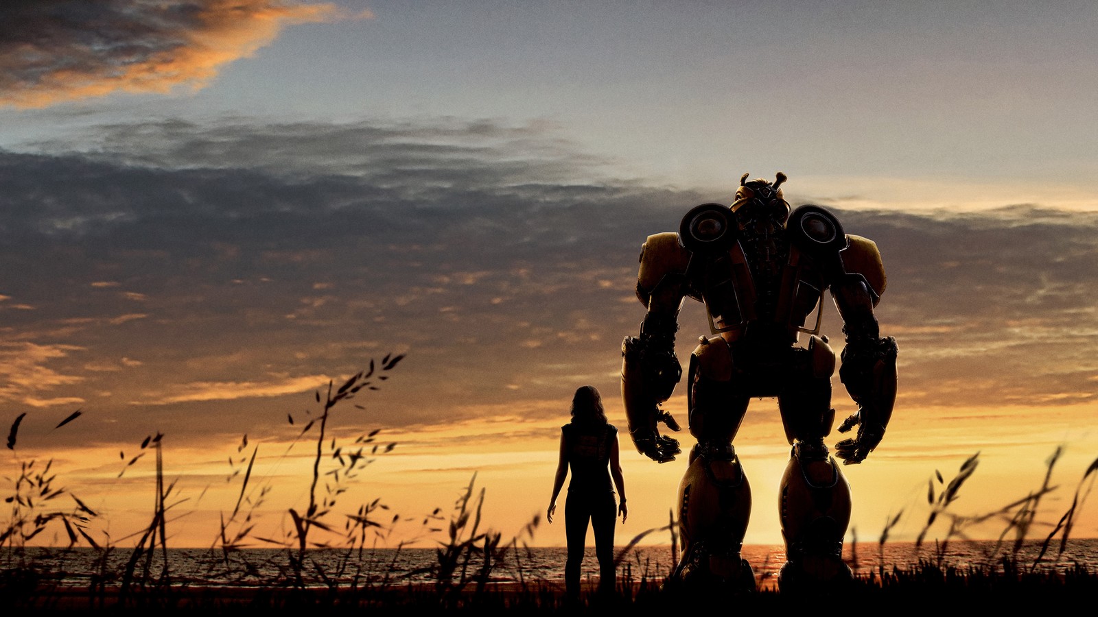 Personaje de la película transformers de pie frente a una puesta de sol con una persona de pie en primer plano (robot, abejorro, transformers, paramount pictures, cartel)