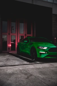 Lebhaft grüner Ford Mustang GT geparkt vor roten Türen.