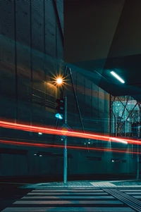 Reflejo urbano nocturno: trazos de luz roja contra la arquitectura azul