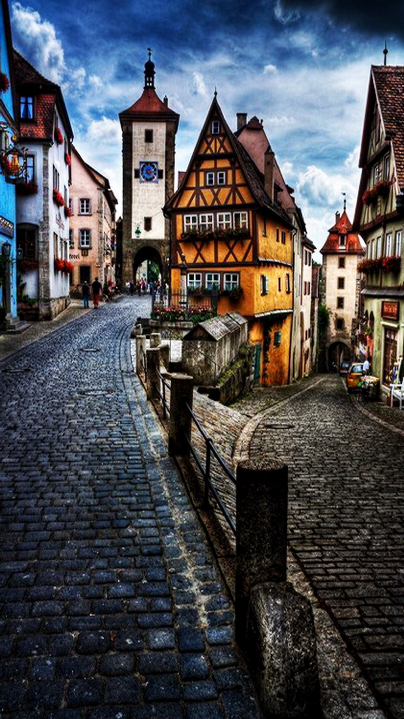 Vista aérea de una calle de adoquines con una torre del reloj al fondo (alemania, casas, calle)