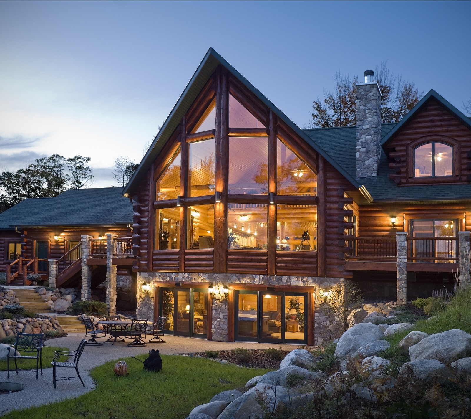 A close up of a large log home with a patio and a fire pit (home, house, mansion)