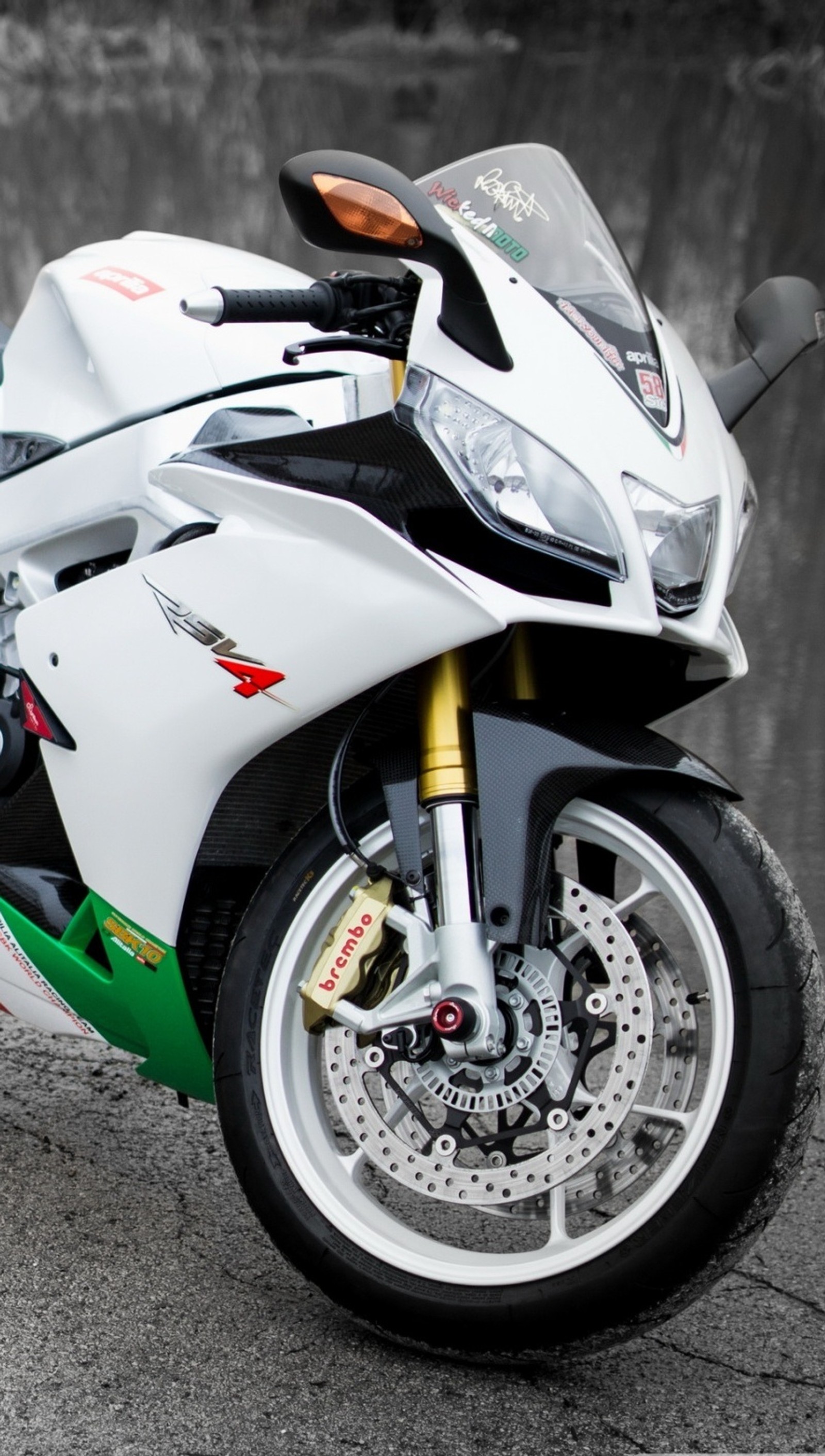 Motorcycle parked on the pavement in front of a wall (aprilia, moto, motorcycle)