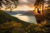 Chèvre majestueuse surplombant un lac serein au lever du soleil