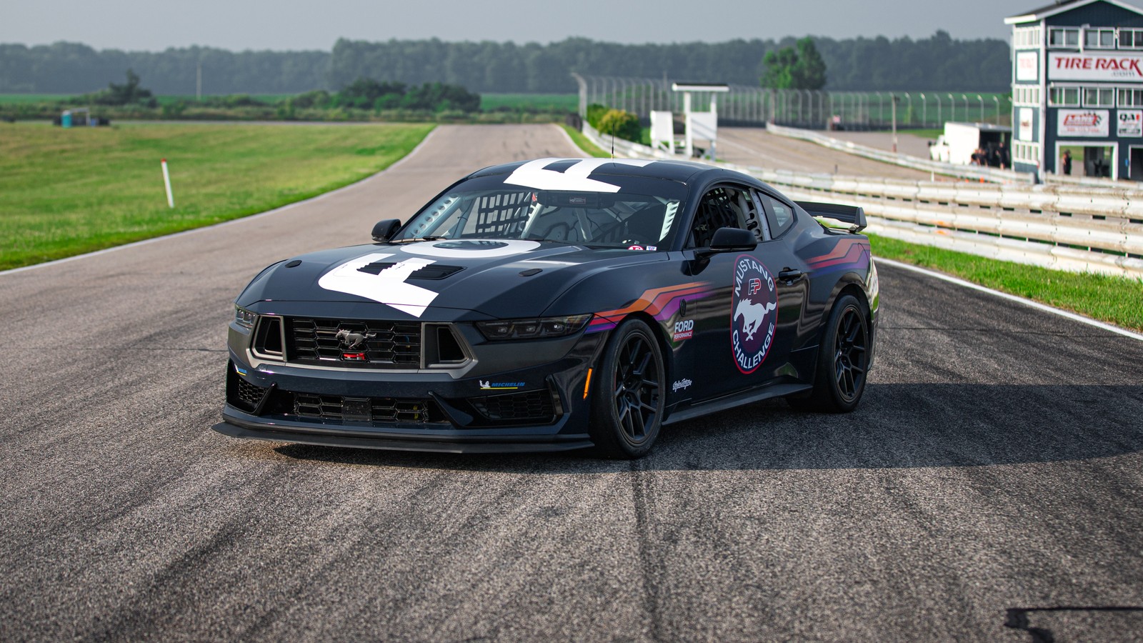 A close up of a car on a race track with a racing flag on it (ford mustang dark horse, 2024, race cars, race track, 5k)