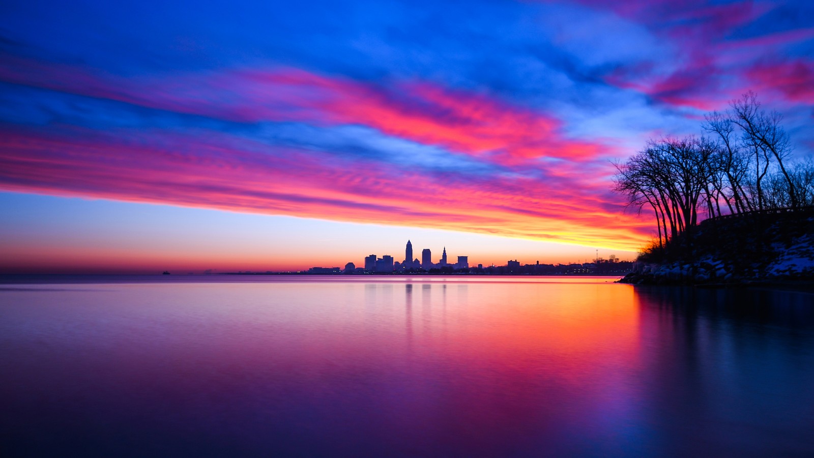 Una vista del horizonte de la ciudad desde un lago al atardecer (atardecer, nubes, cielo, escenario, horizonte)