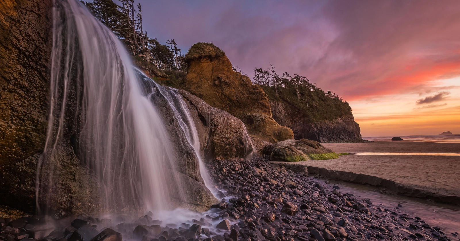 Uma cachoeira caindo de um penhasco rochoso no oceano ao pôr do sol (cachoeira, natureza, corpo de água, água, paisagem natural)