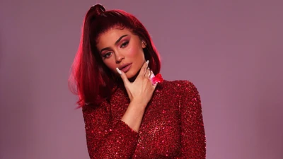 Kylie Jenner in a sparkling red outfit against a soft pink background.