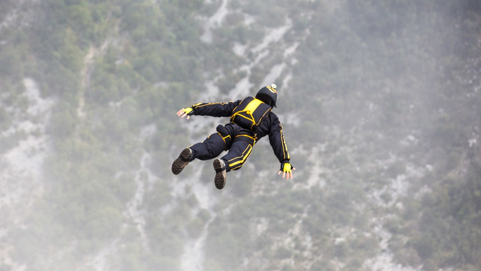 Un homme arabe en costume jaune et noir vole dans les airs (base jumping, sport extrême, sports aériens, parachutisme, cascadeur)