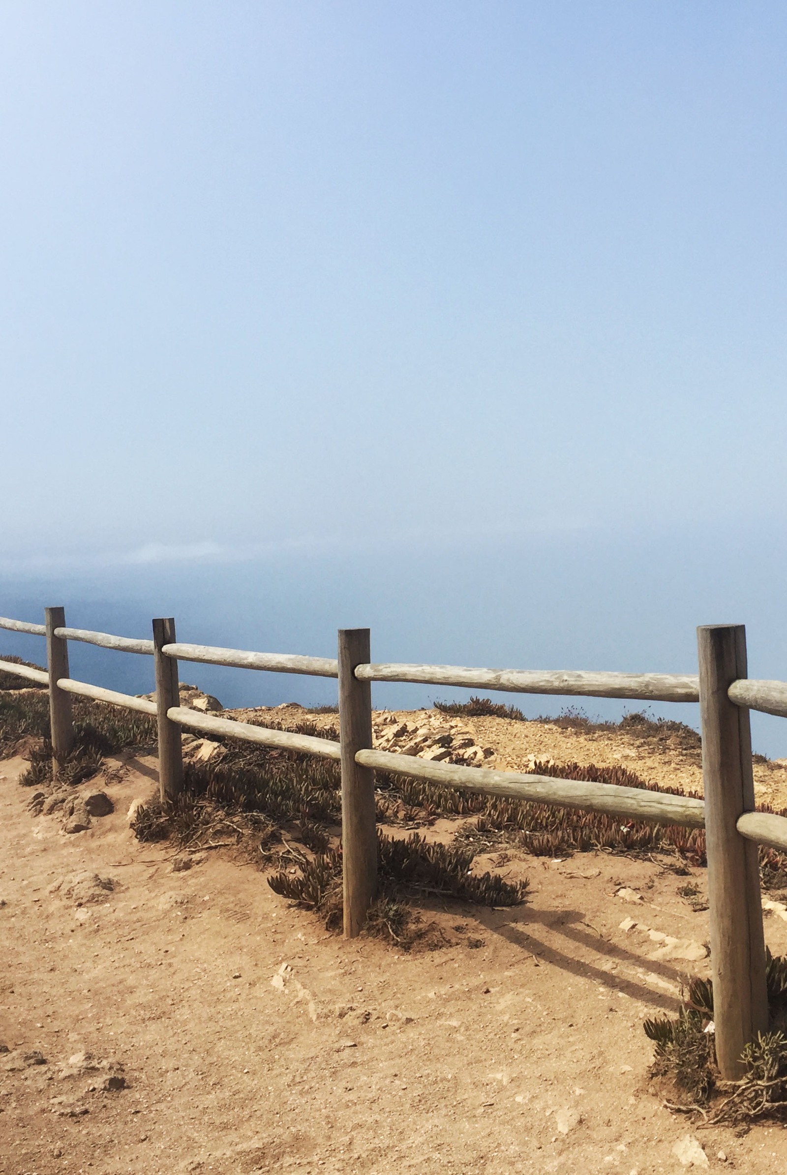 There is a wooden fence on the side of a hill (cabo da roca, city, landscape, nature, portugal)