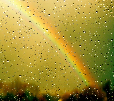 Arc-en-ciel encadré par une fenêtre parsemée de gouttes de pluie