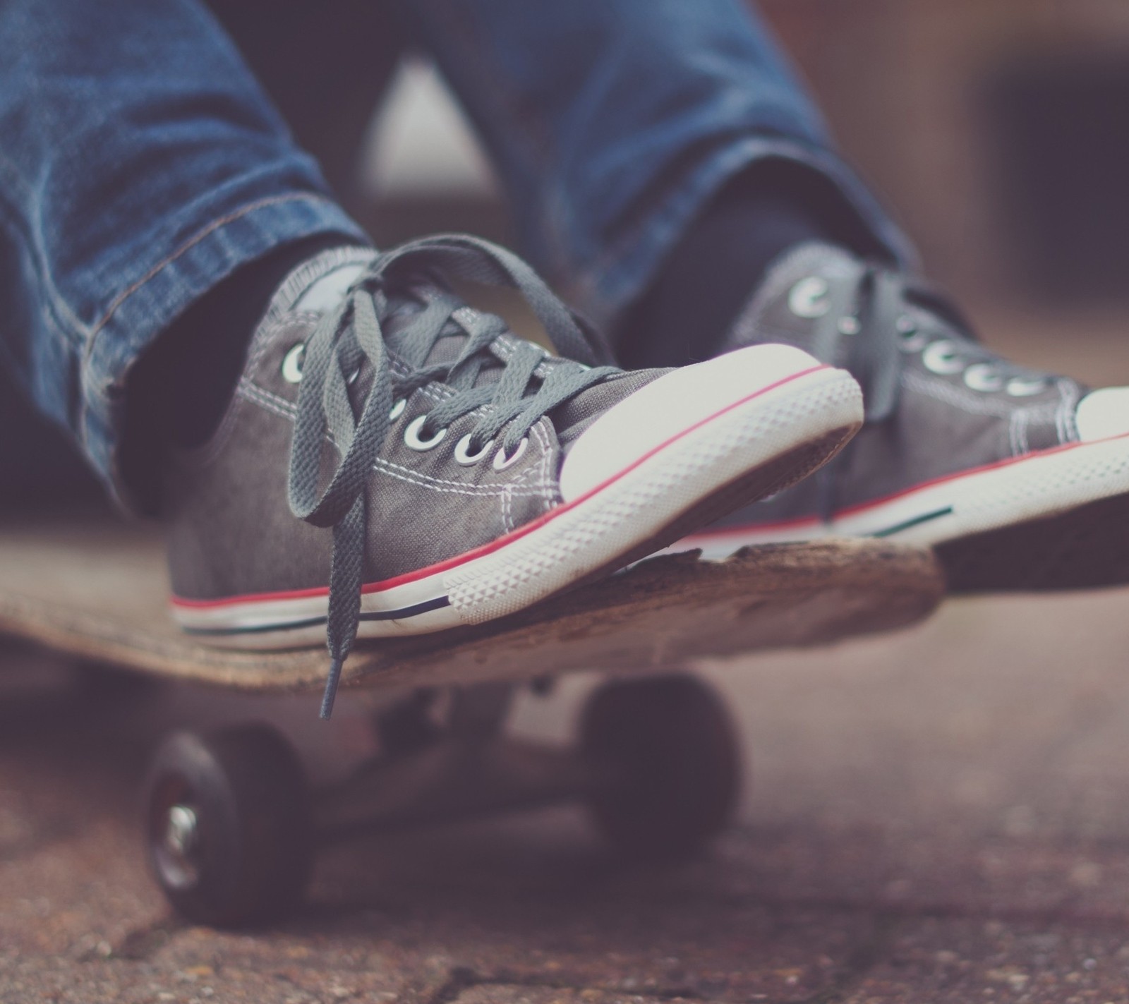 Someone is riding a skateboard on a sidewalk with their feet on it (allstar, skate, skateboard)