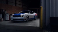 Dodge Challenger 2021 dans un cadre de garage d'humeur, mettant en valeur son branding Mopar et sa peinture bleu et blanc frappante.