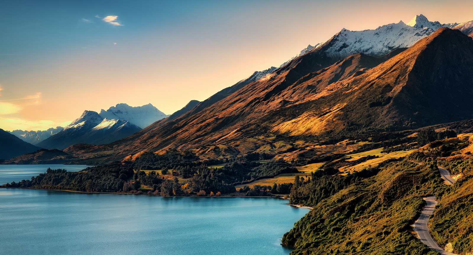 Uma vista de um lago e montanhas com uma estrada passando por ele (lago wakatipu, montanhas, queenstown, nova zelândia, new zealand)