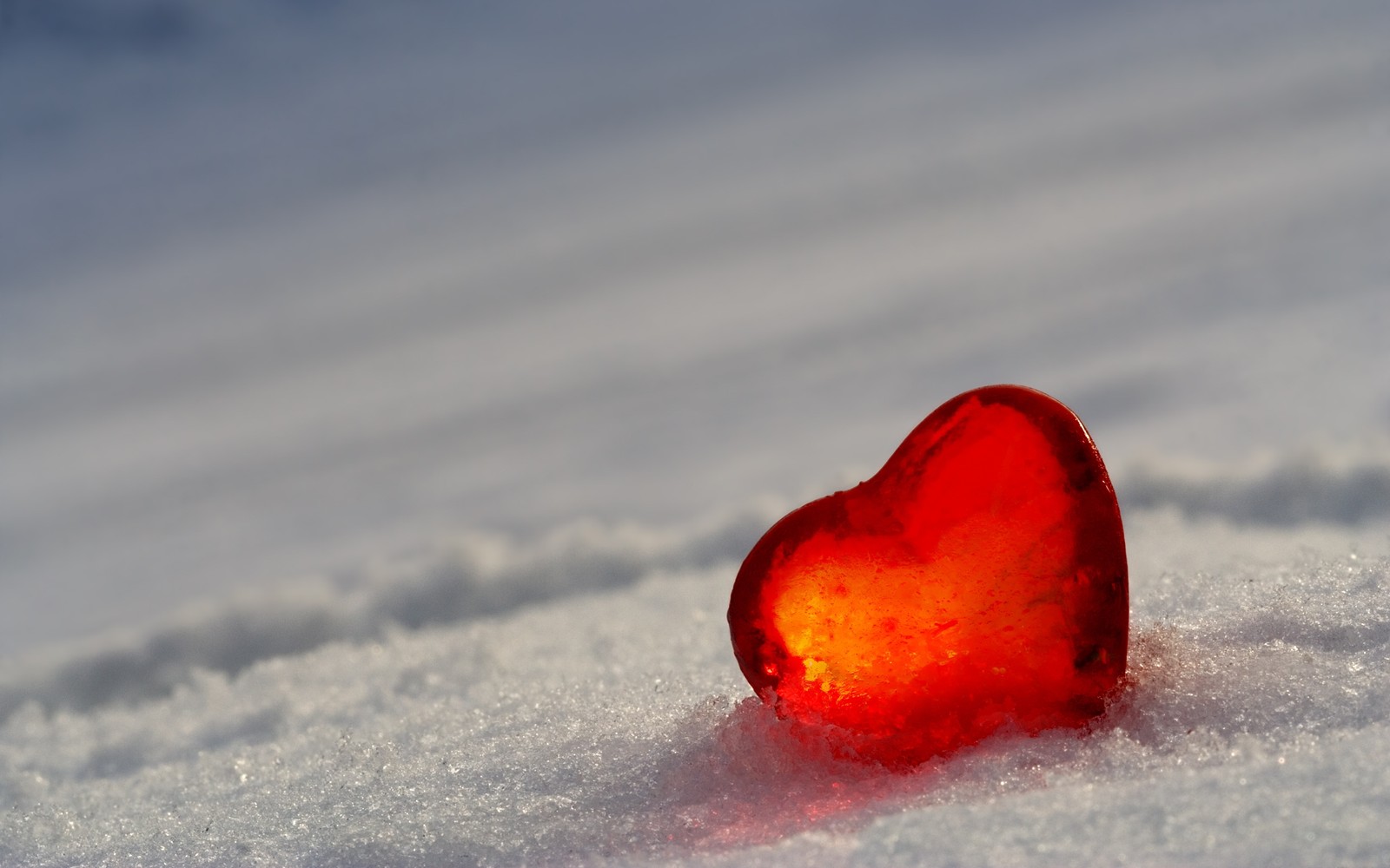 Vue aérienne d'un verre en forme de cœur posé dans la neige par un jour ensoleillé (neige, cœur, hiver, amour, glace)