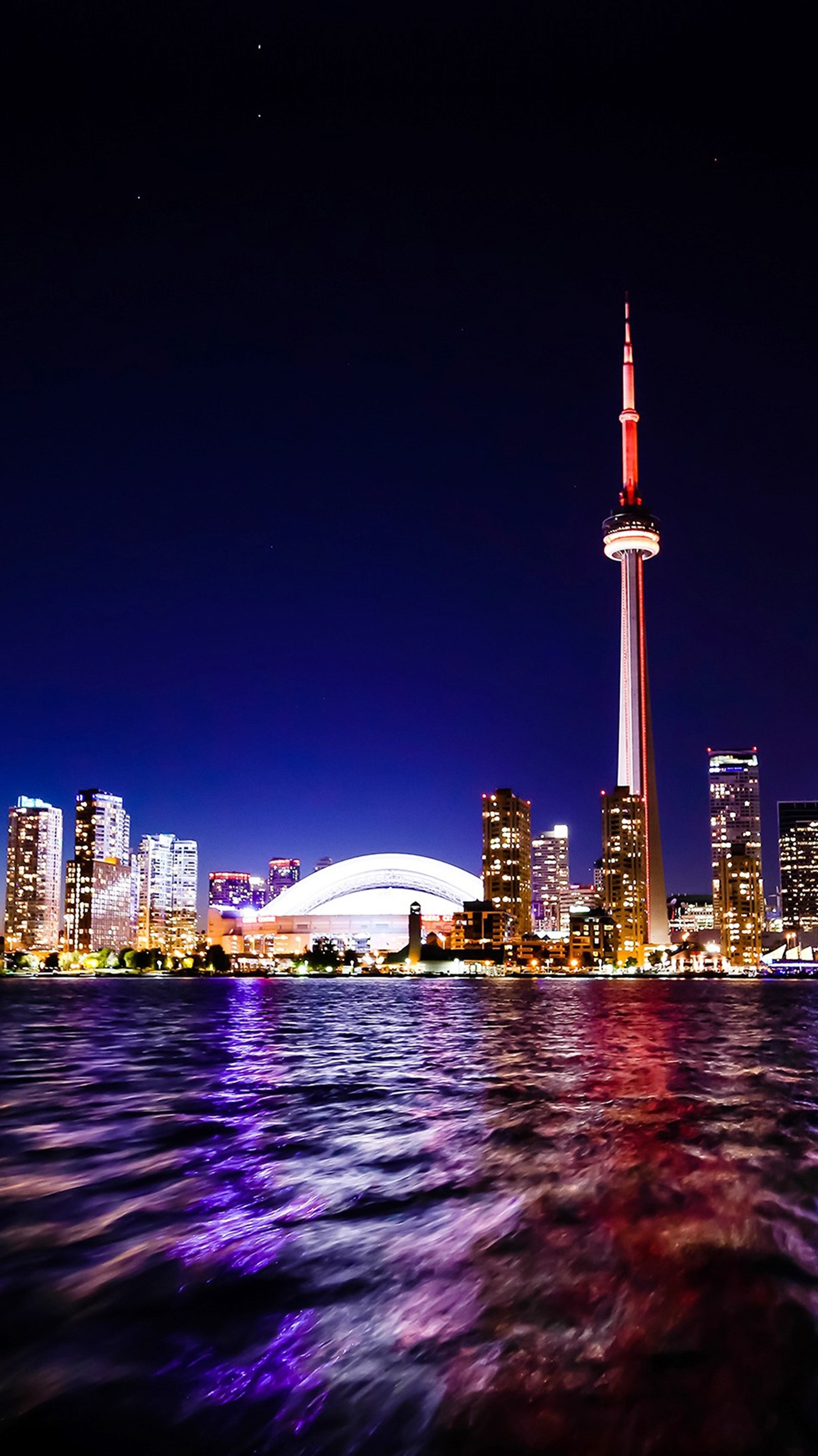 Una vista panorámica del horizonte de la ciudad por la noche con un bote en el agua (canadá, vista nocturna de la ciudad, lago, toronto)