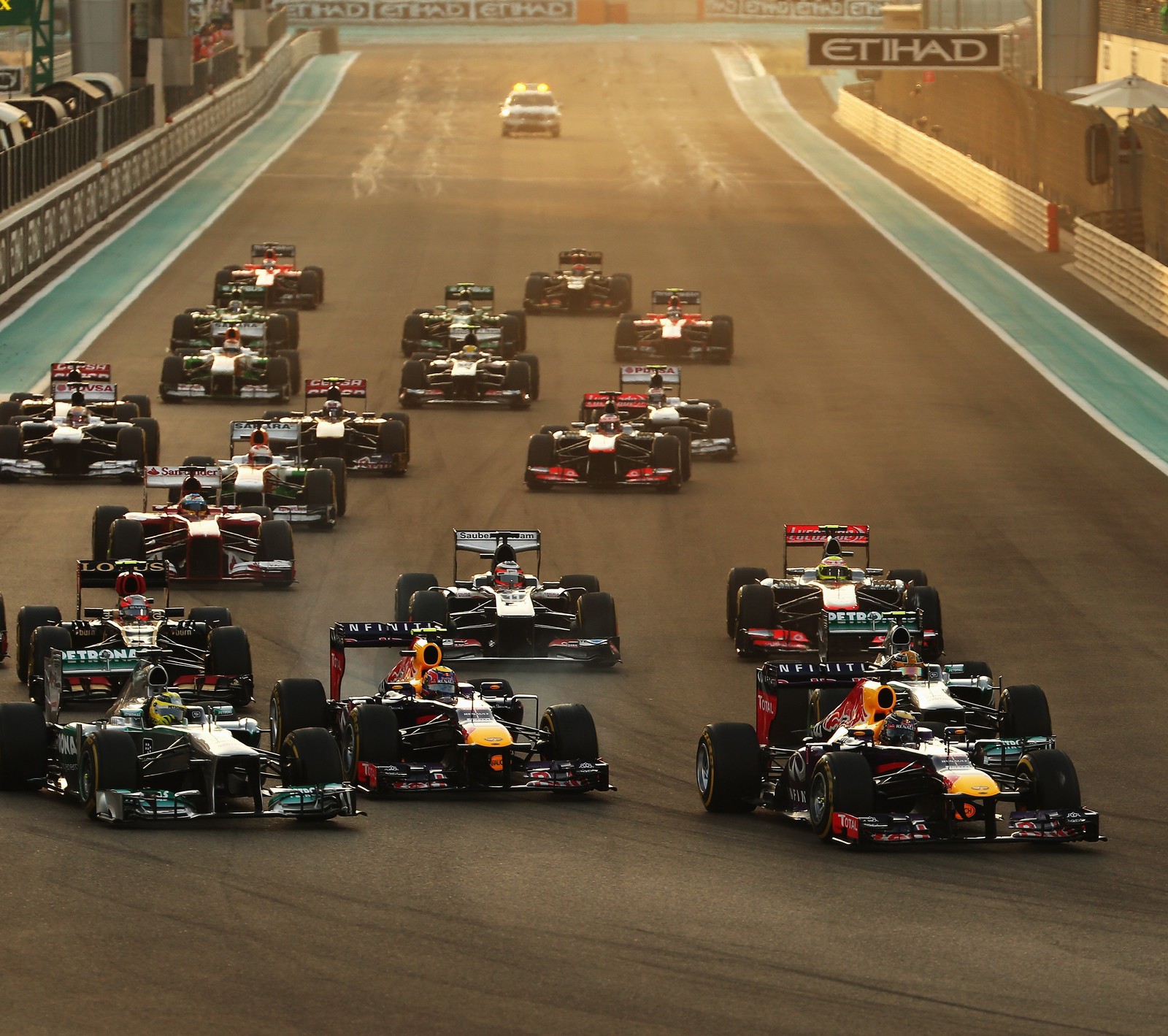 Arafed race cars racing on a track with a lot of spectators (formula 1, lotus, red bull)