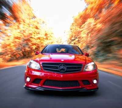 Dynamischer roter Mercedes-Benz C63 AMG in Bewegung durch herbstliche Landschaft