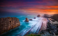 Exposição longa serena da Playa de Portio ao crepúsculo, mostrando a costa rochosa e as ondas suaves