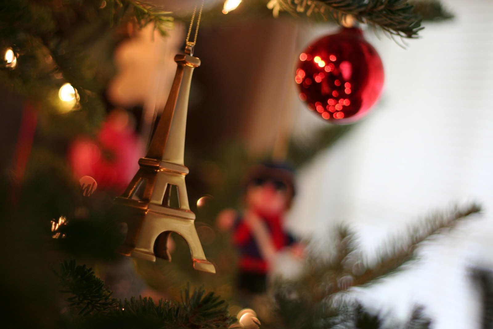 There is a christmas tree with a small eiffel tower ornament (christmas day, holiday, christmas tree, christmas ornament, christmas)