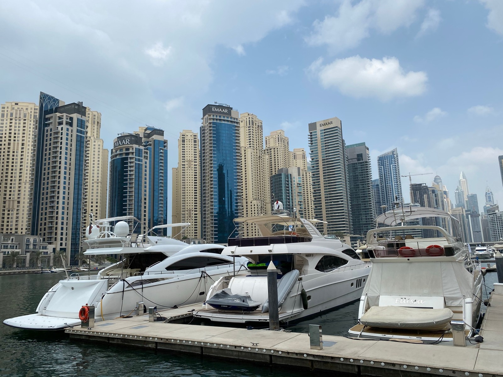 Des bateaux amarrés dans une marina avec une ville en arrière-plan (dubaï, dubai, marina de dubaï, port, eau)