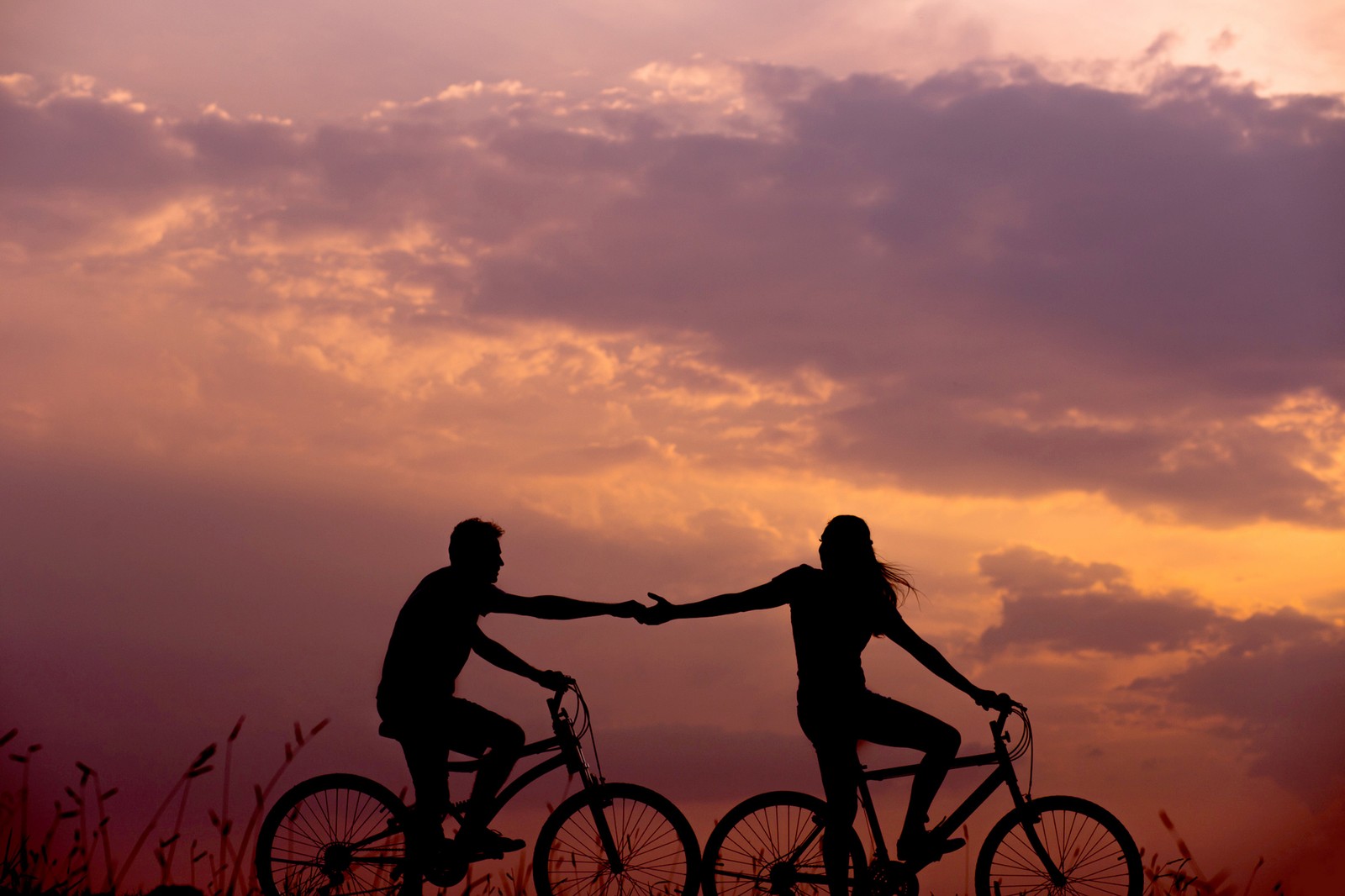 Ils font du vélo au coucher du soleil (amour, valentin, cœurs)