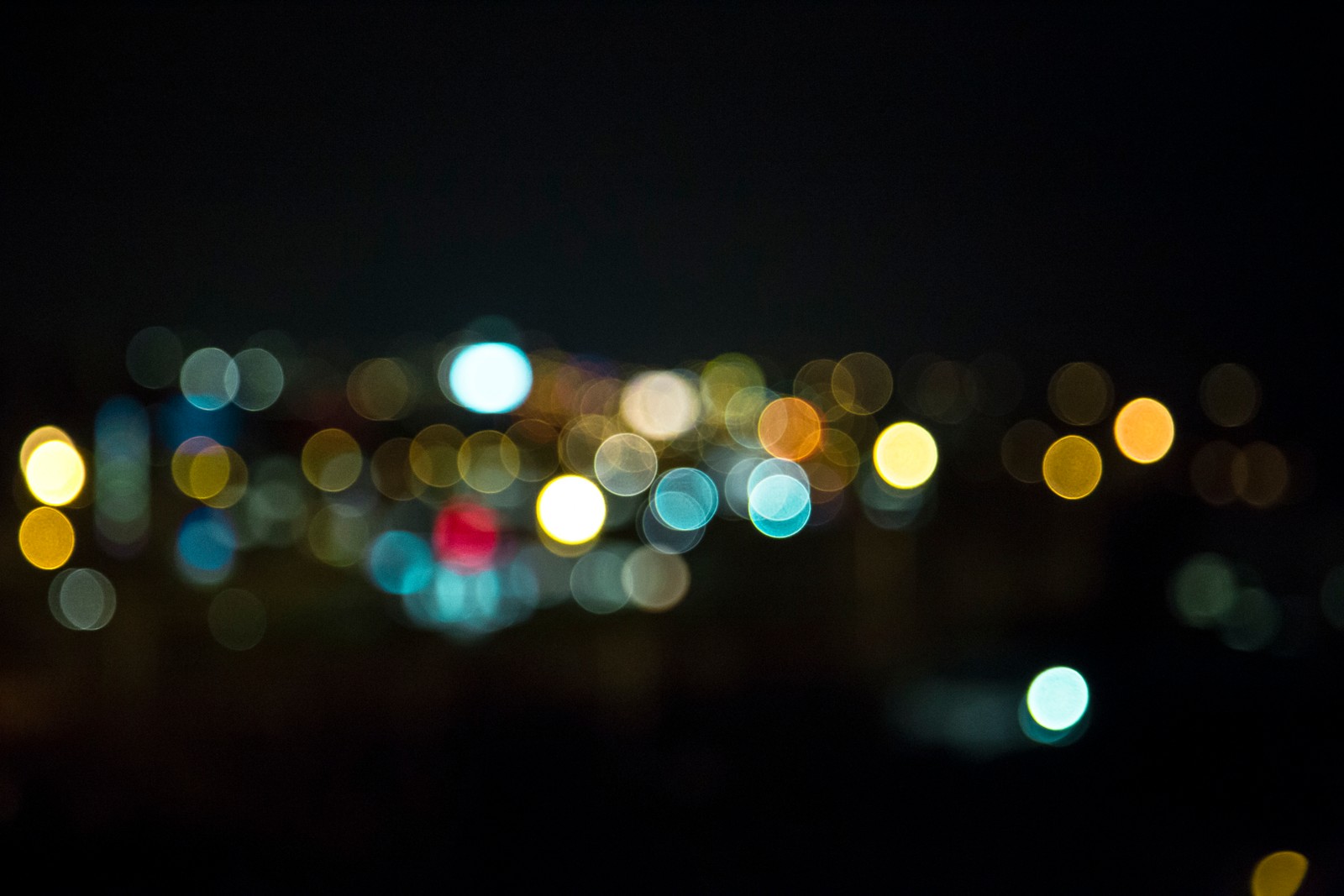 Luzes desfocadas de uma cidade à noite com um céu escuro (bokeh, luz, iluminação, noite, escuridão)