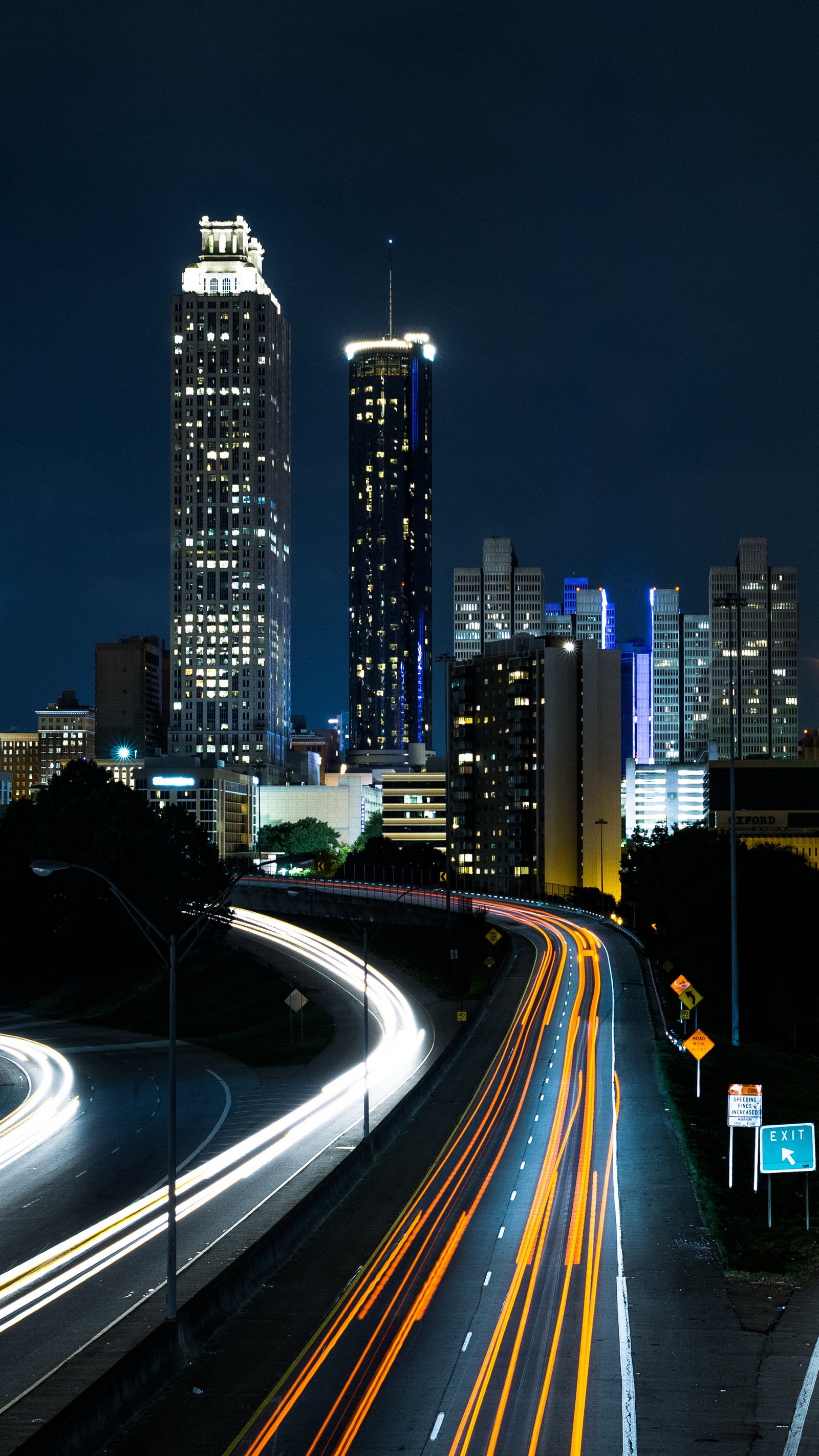 Vista nocturna de una ciudad con una carretera (rascacielos, edificio, torre, iluminación automotriz, infraestructura)