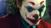 Primer plano intenso de Joaquin Phoenix como el Joker, mostrando su maquillaje icónico y su expresión angustiada.