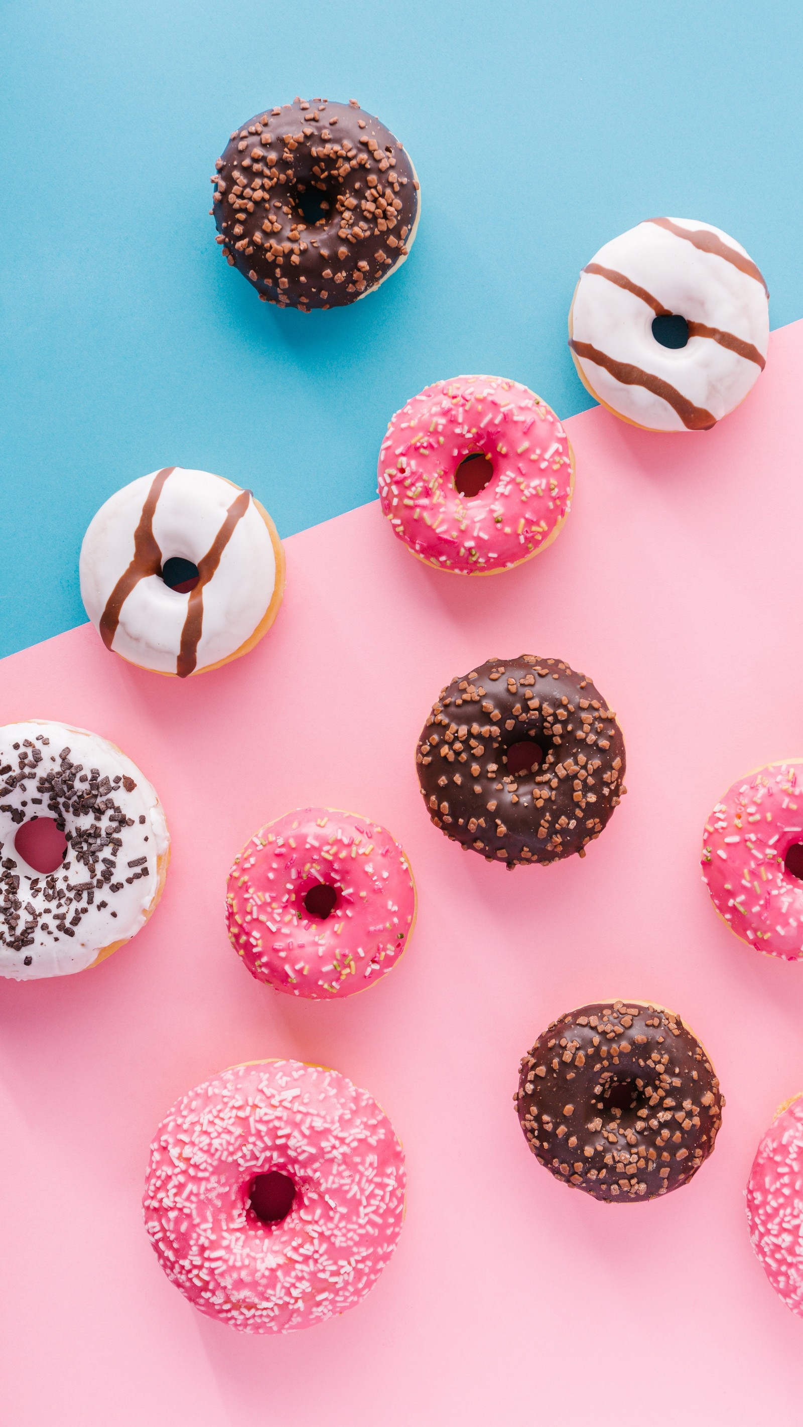 Hay muchos tipos diferentes de donuts sobre una superficie rosa y azul (donut, colorido, textil, púrpura, juguete)