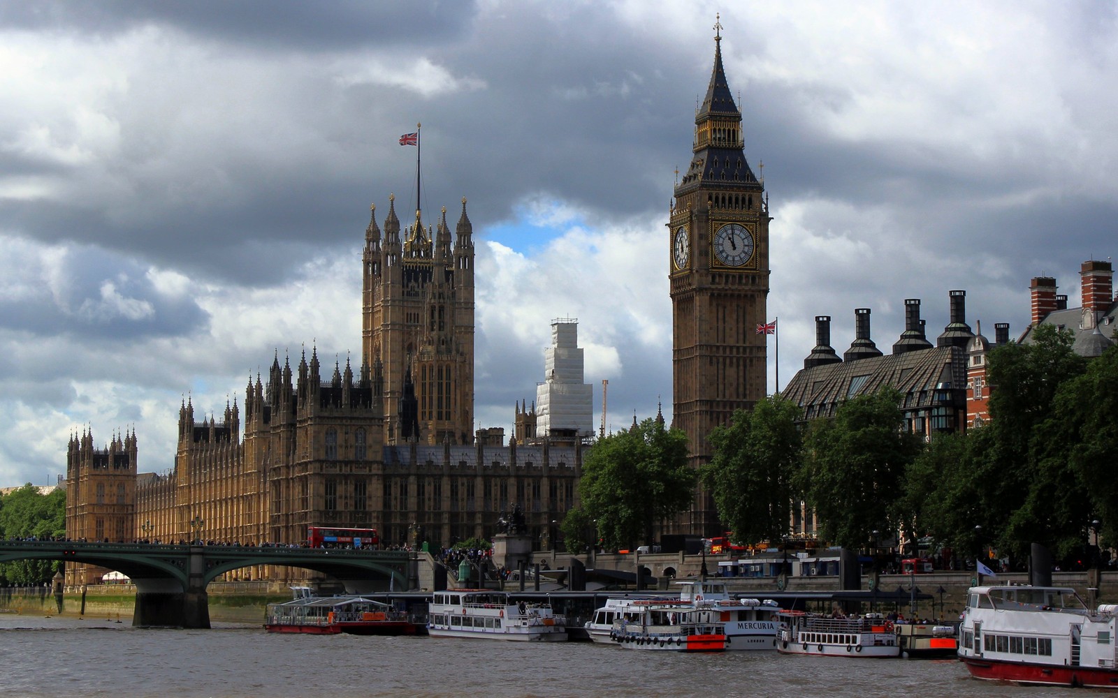 Jirafas y botes están en el agua cerca de un puente (casas del parlamento, big ben, río támesis, hito, ciudad)