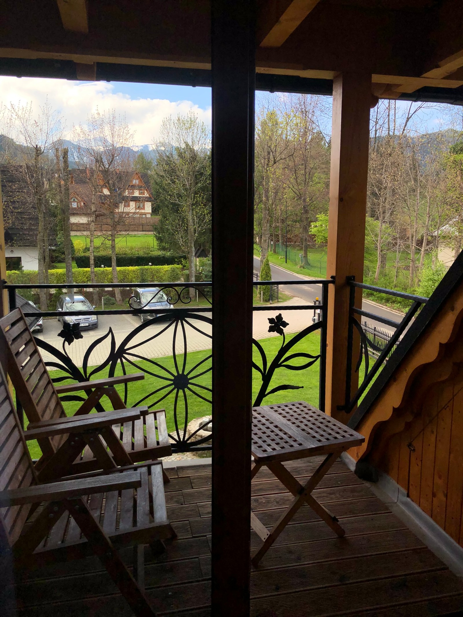 There is a wooden chair on a balcony with a view of a lake (house, real estate, porch, balcony, wood)