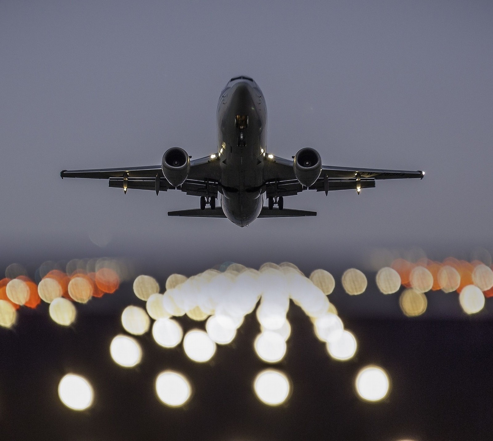 Um avião pousando à noite com luzes ao fundo (abej, beograd, blast off)