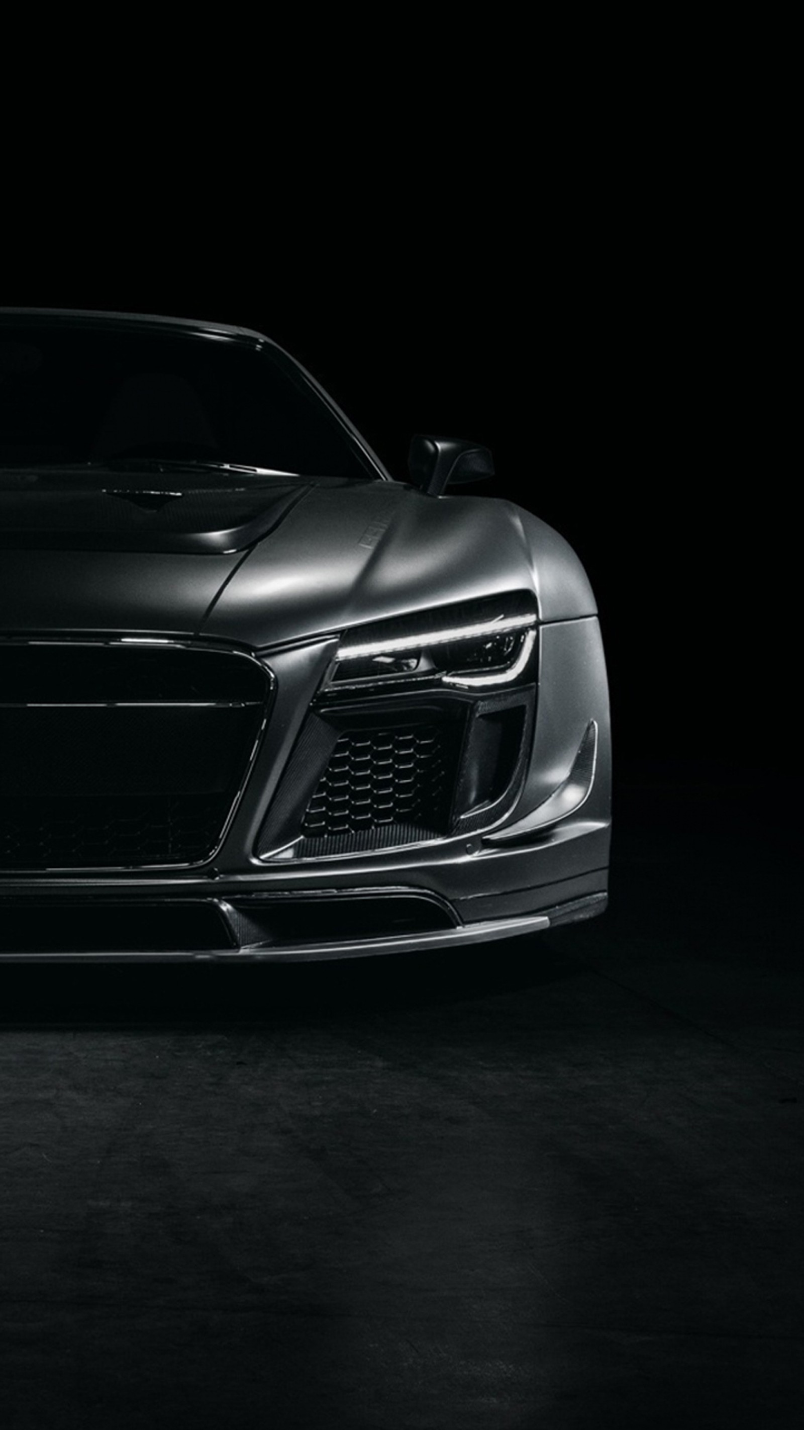 A close up of a black sports car in a dark room (audi, german, r8, supercar)