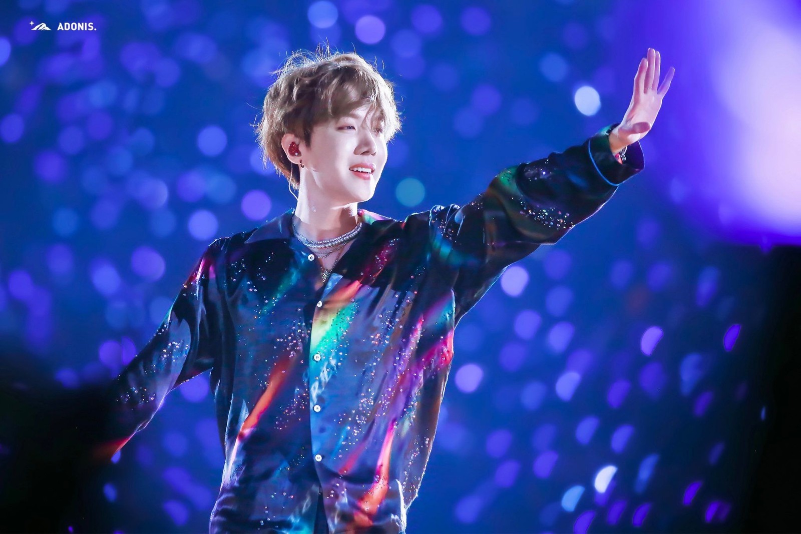 A man in a colorful shirt is holding his hands up (bts, our hope)