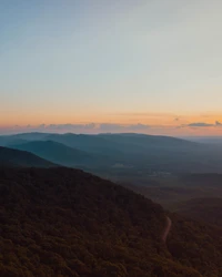 Silhouette de una cresta montañosa bajo un sereno cielo de atardecer, destacando las capas atmosféricas del paisaje de tierras altas.