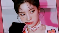 Dahyun do TWICE exala carisma com uma maquiagem marcante e uma expressão brincalhona, apresentada em um ambiente vibrante e colorido.