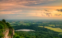 Stunning Sunset Over a Lush Valley and Serene Water Body