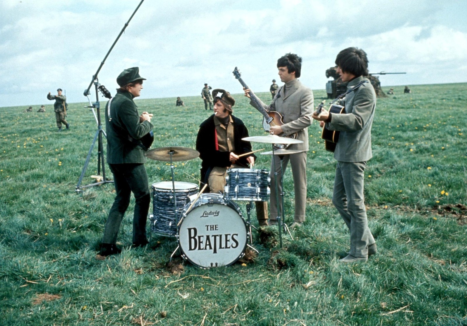 Imagen borrosa de un grupo de hombres tocando música en un campo (the beatles, recreación, árbol, hierba, planta)