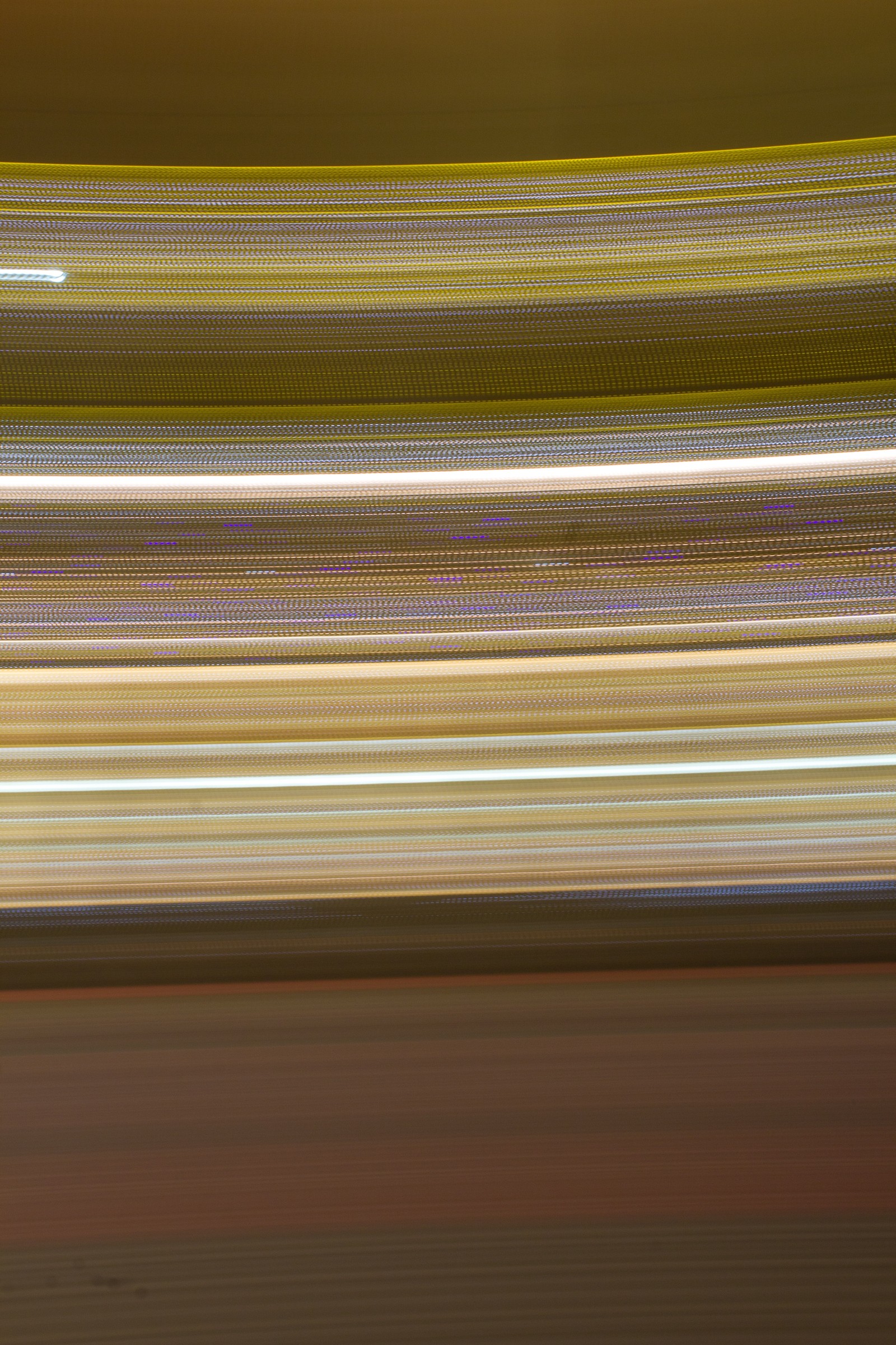 Blurred image of a person riding a skateboard on a city street (angle, yellow, line, beige, light)