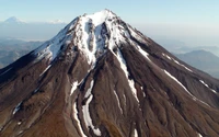 Majestoso estratovulcão coberto de neve na Kamchatka, exibindo um terreno vulcânico acidentado e características glaciares.