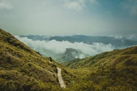 Paisagem montanhosa serena com nuvens ondulantes e estrada cênica