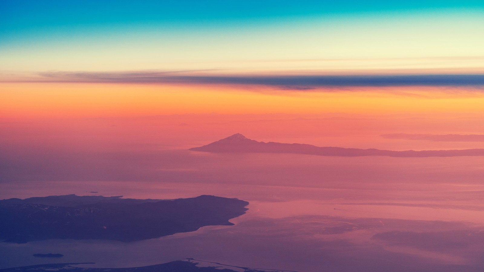 A view of a sunset over a body of water and mountains (sunset, clouds, aerial view, islands, nature)