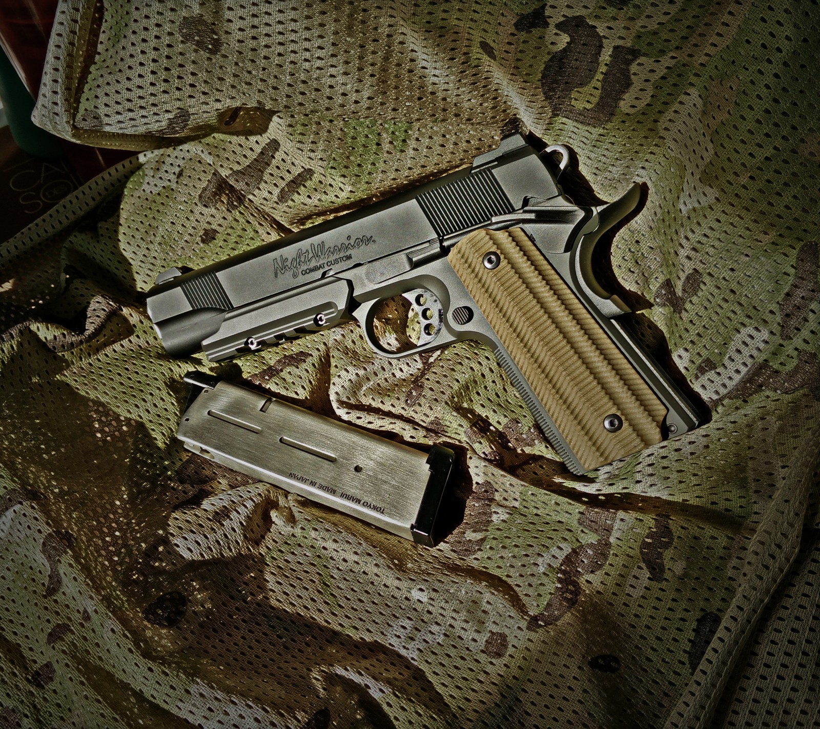 Il y a un pistolet qui repose sur une couverture. (1911, airsoft, armée, combat, marui)