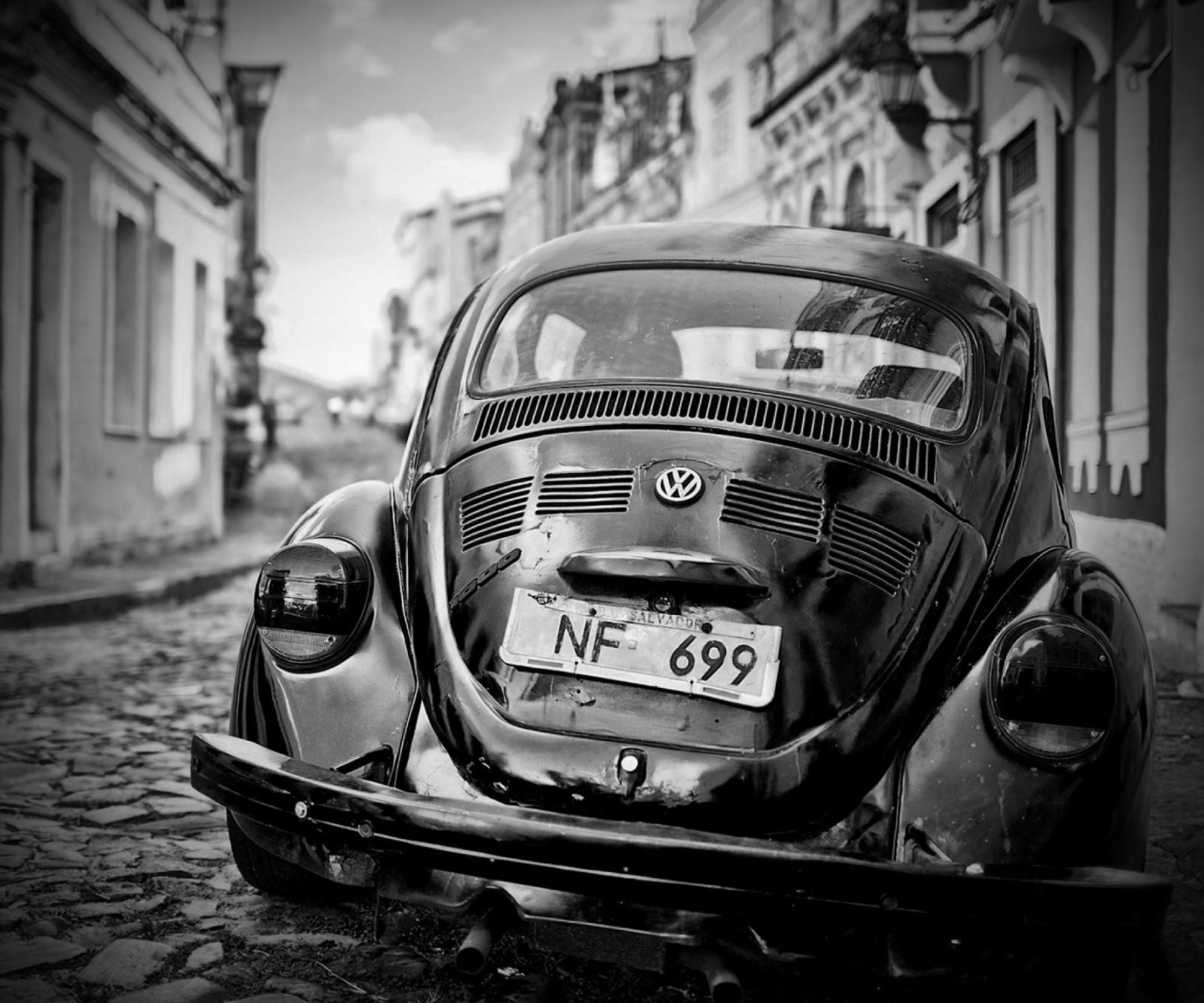 Photographie en noir et blanc d'une voiture garée sur une rue pavée (auto, noir, noir et blanc, voiture, sombre)