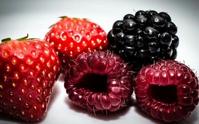 Un assortiment vibrant de fraises, de mûres et de framboises fraîches.